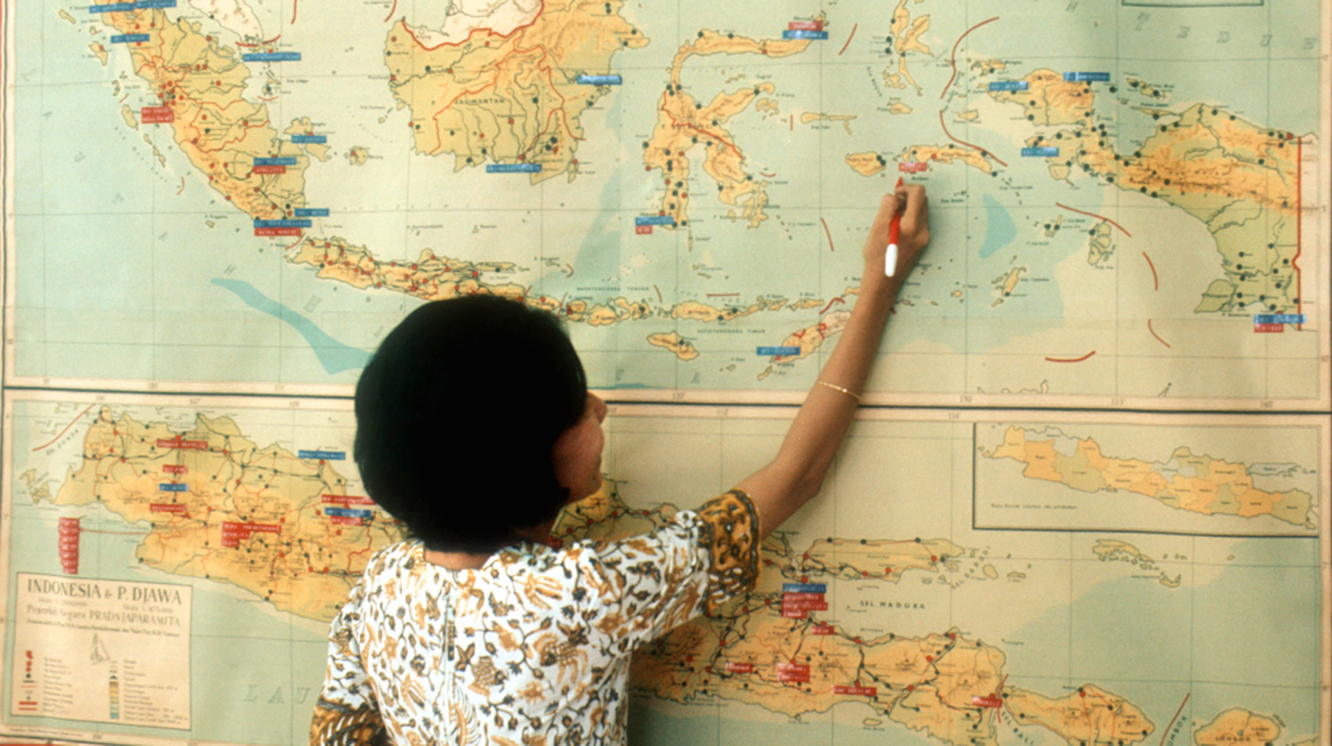 Eine Schülerin steht vor einer Landkarte von Indonesien