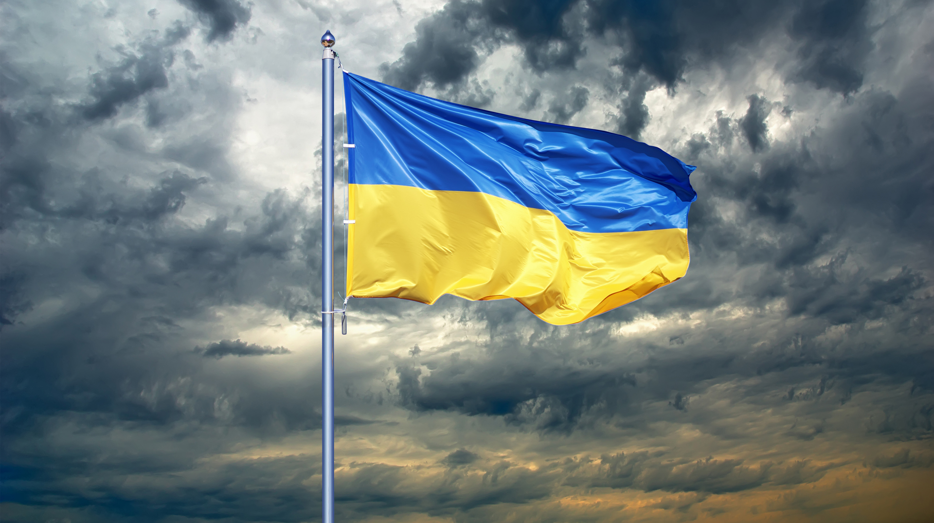 Flagge der Ukraine vor dunklen Wolken