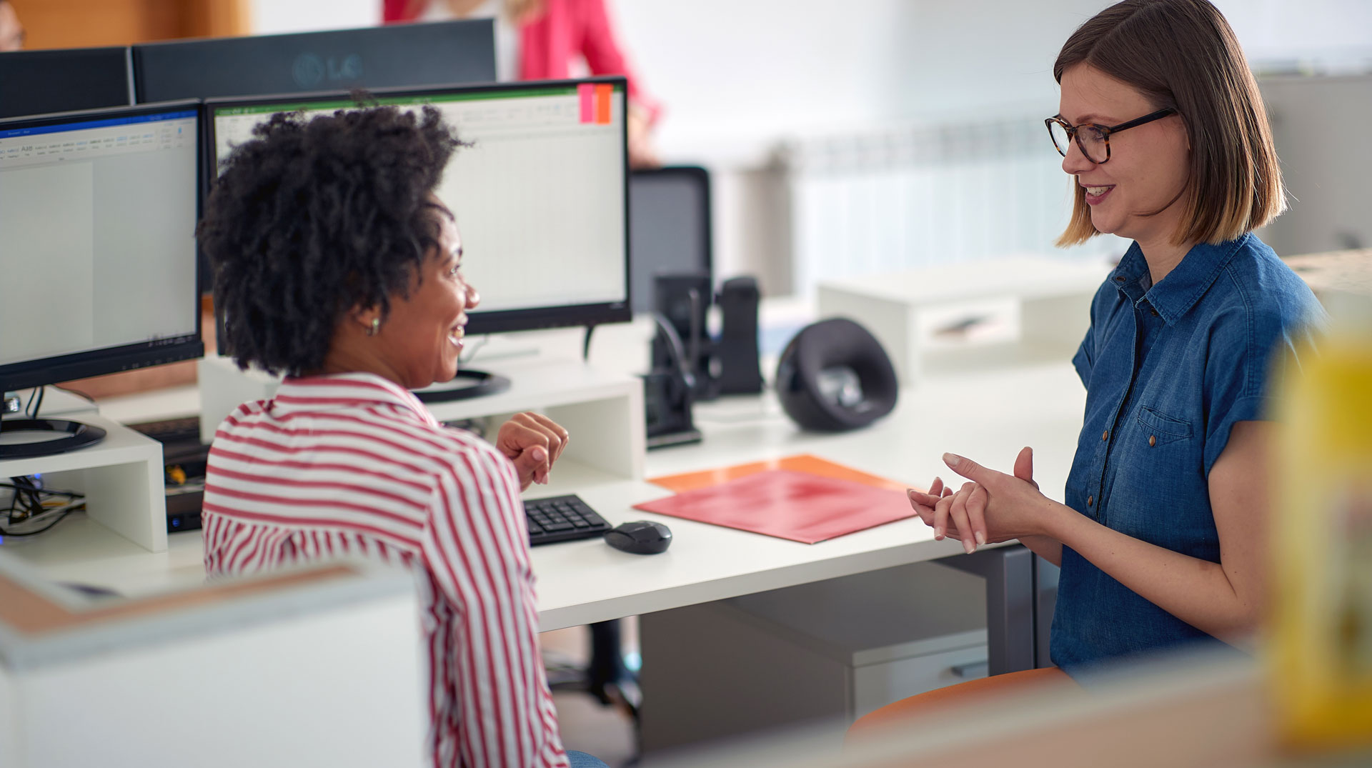 Zwei Frauen sitzen an einem Computer und schauen Berichte an