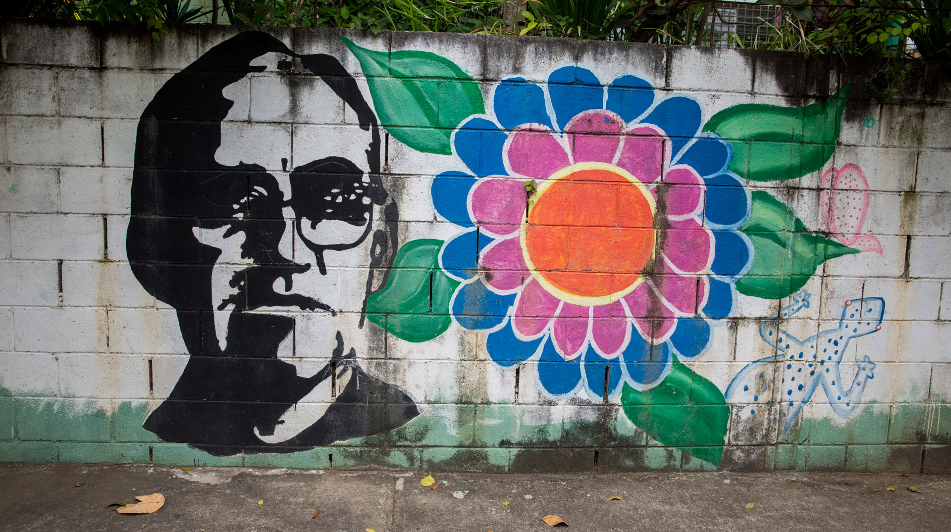 Stilisiertes Bild des heiligen Óscar Romero auf einer vom tropischen Klima verwitterten Mauer