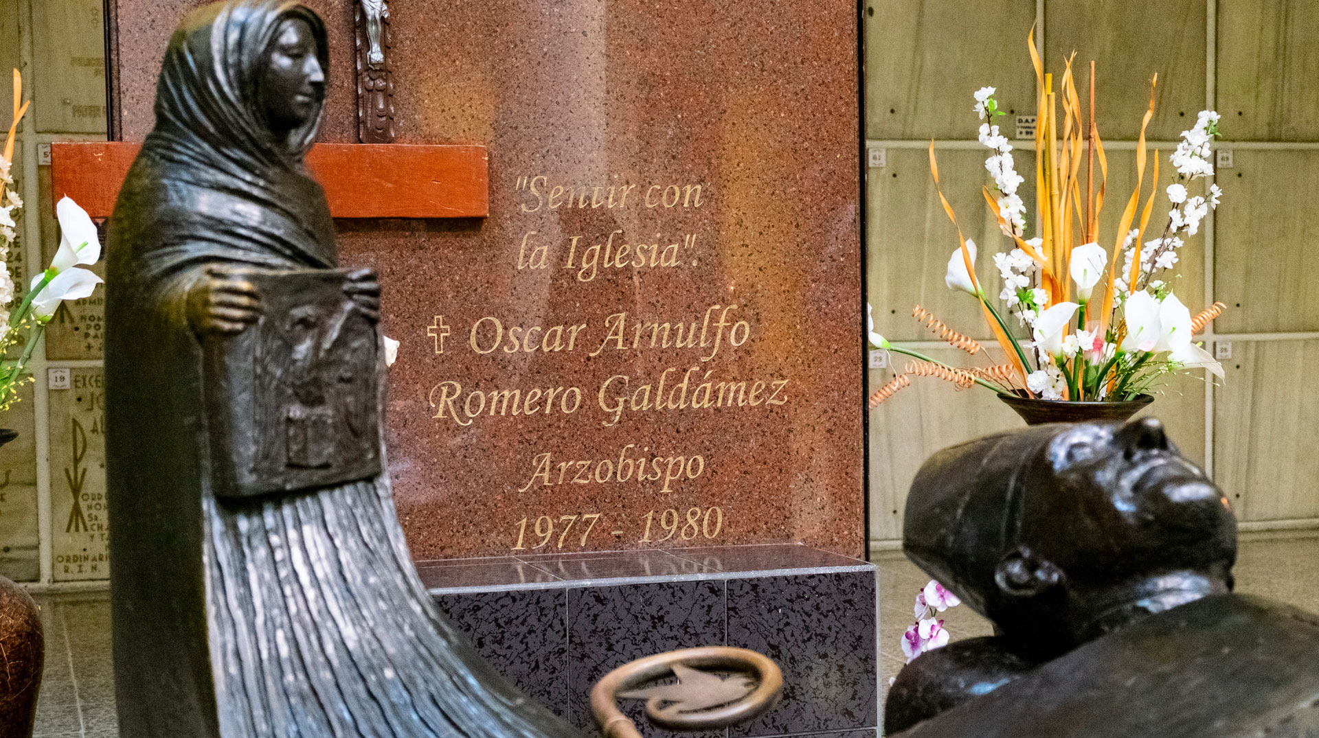 Die Grabstätte des heiligen Óscar Romero mit einer Bronzebüste sowie einem Grabstein mit der Aufschrift "Sentir con la Iglesia".