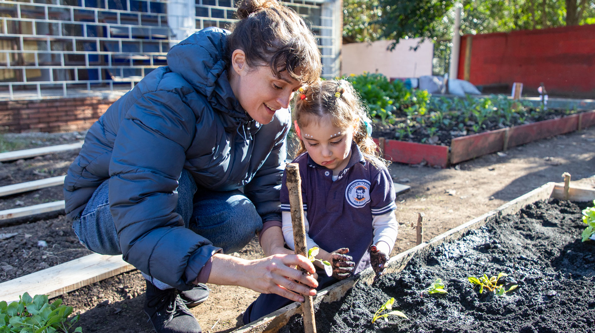 Friederike Becht pflanzt mit den jüngsten Schülerinnen und Schülern Gemüse im Schulgarten. 