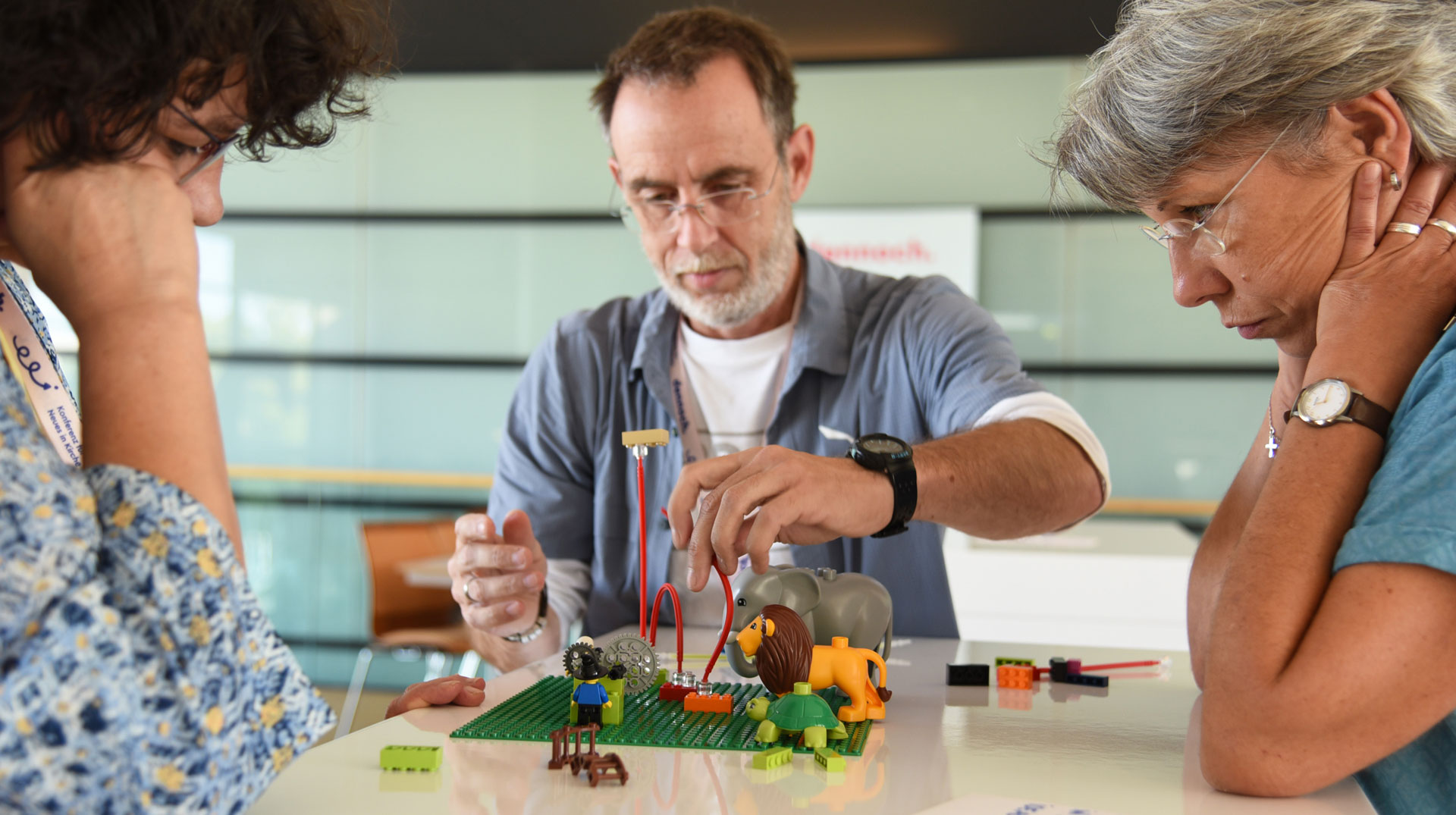 Christine Prothmann, Martin J. Müller und Diana Fleuchaus (von links) bauen mit Legosteinen eine Version von Kirche in vielfältiger Gestalt. (Dennoch Konferenz 2023)