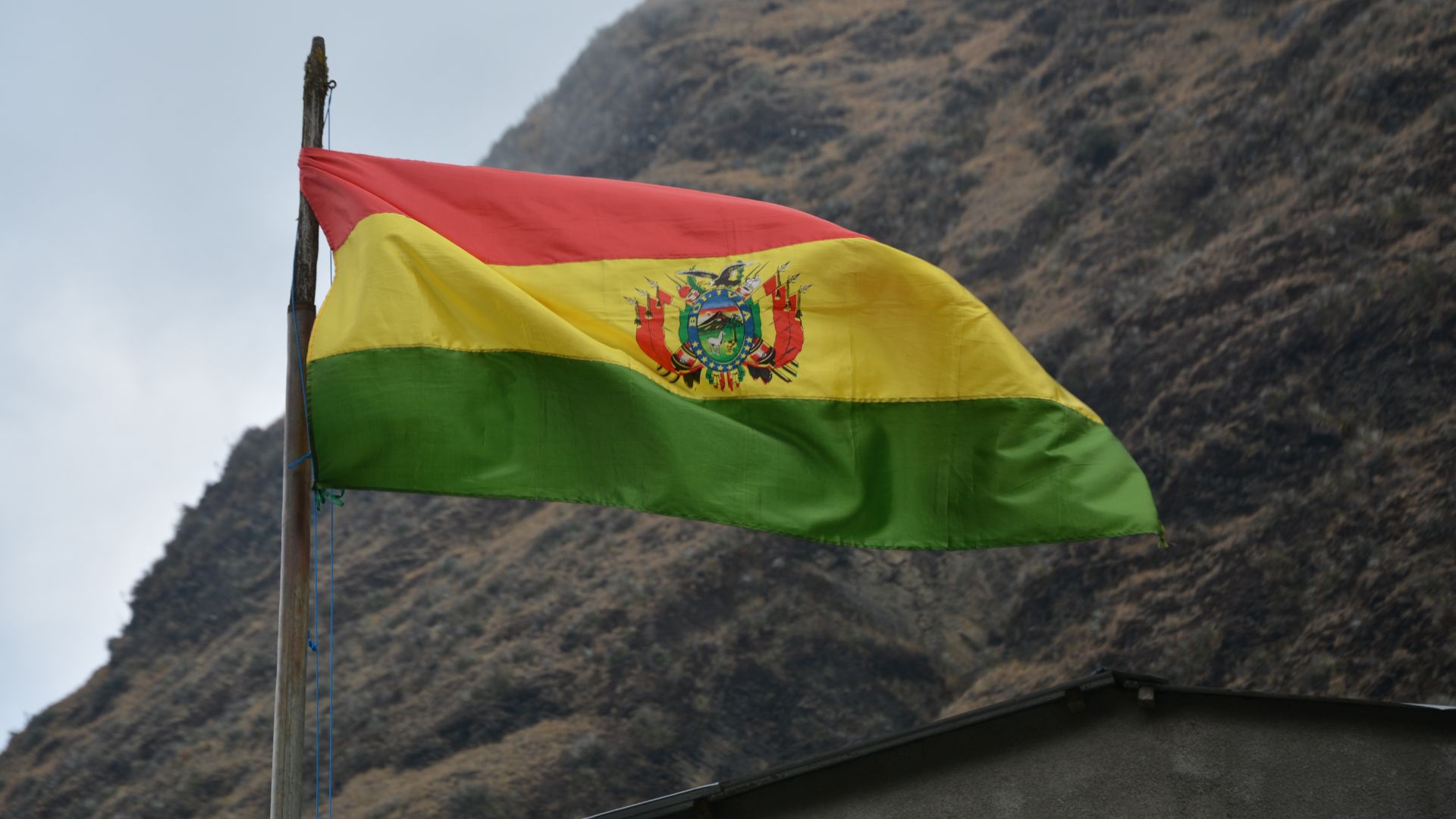 Die Flagge Boliviens vor einem Berghang
