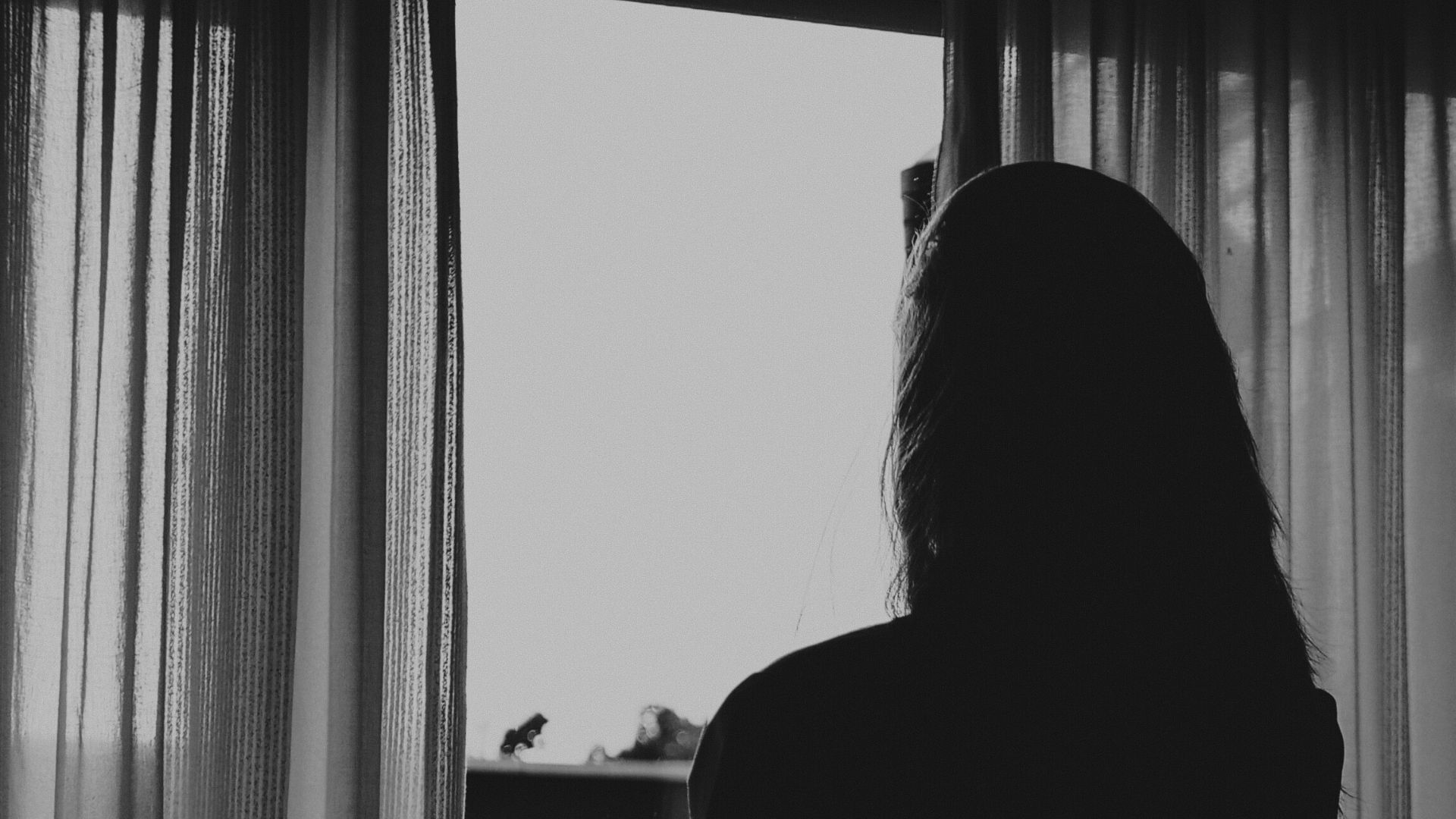 Frauensilhouette am Fenster im Gegenlicht