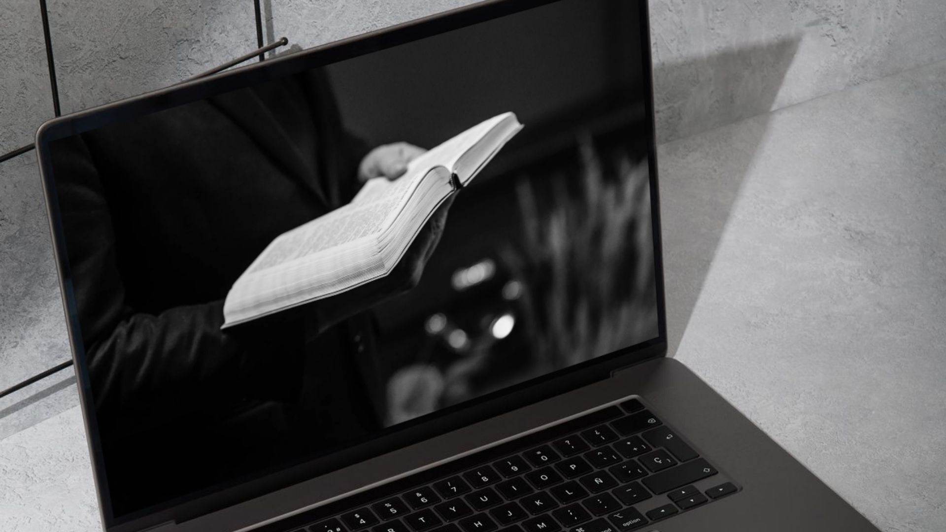 Auf einem Computerbildschirm ist folgendes Motiv zu sehen: Ein Mann (Pastor/Katechet) hält ein Buch in der Hand.