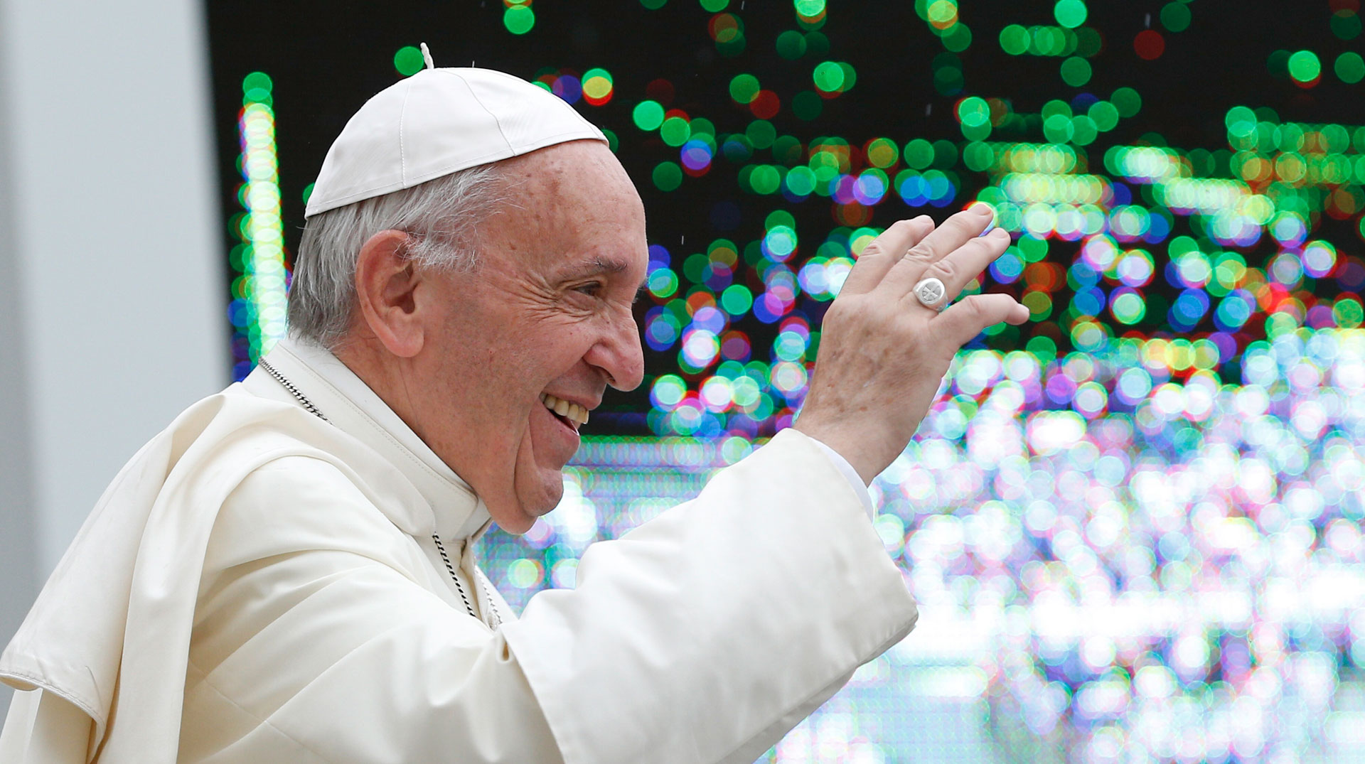 Papst Franziskus lächelt und grüßt Menschen
