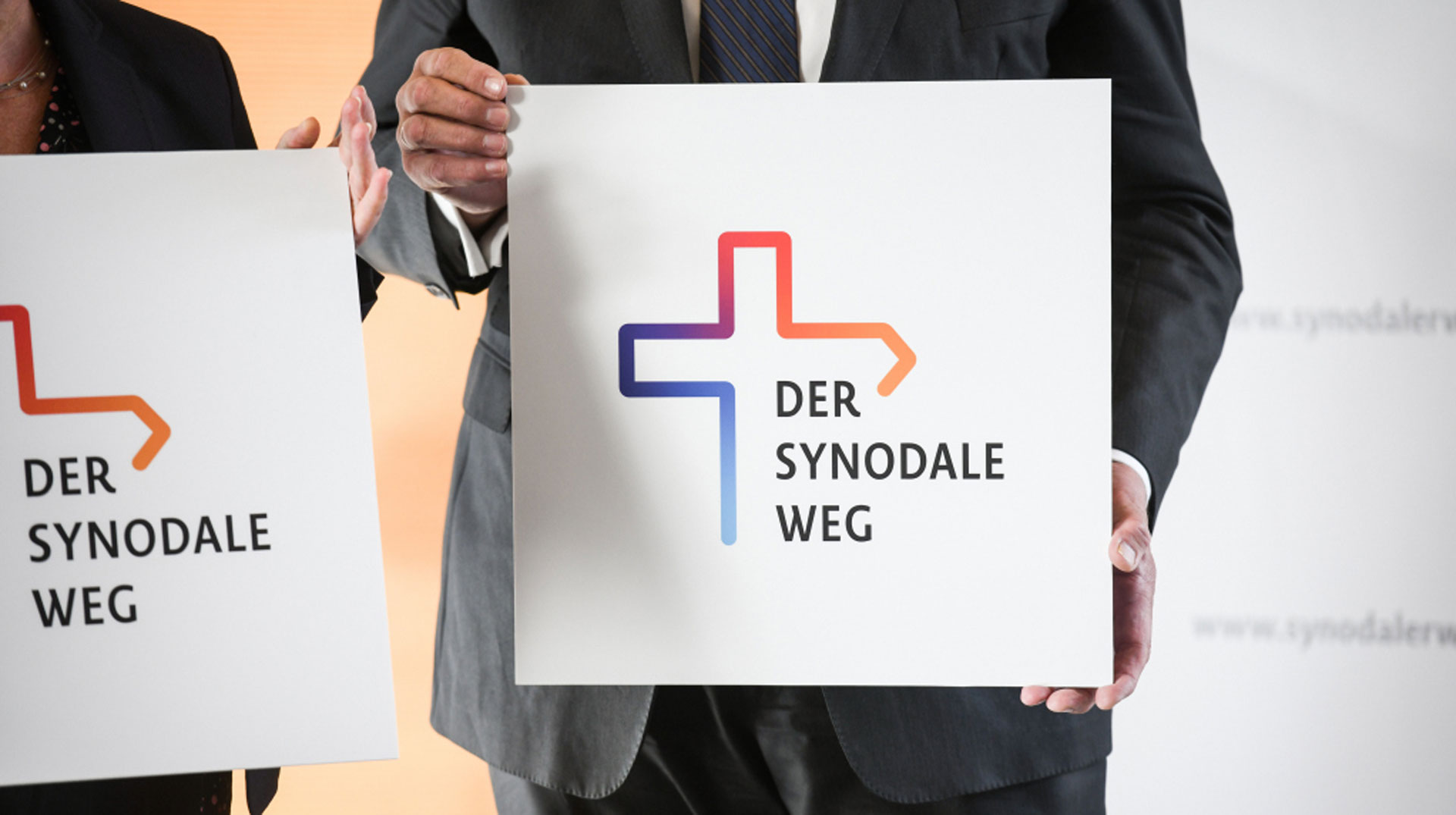 Hände halten ein Schild mit der Aufschrift "Der Synodale Weg"