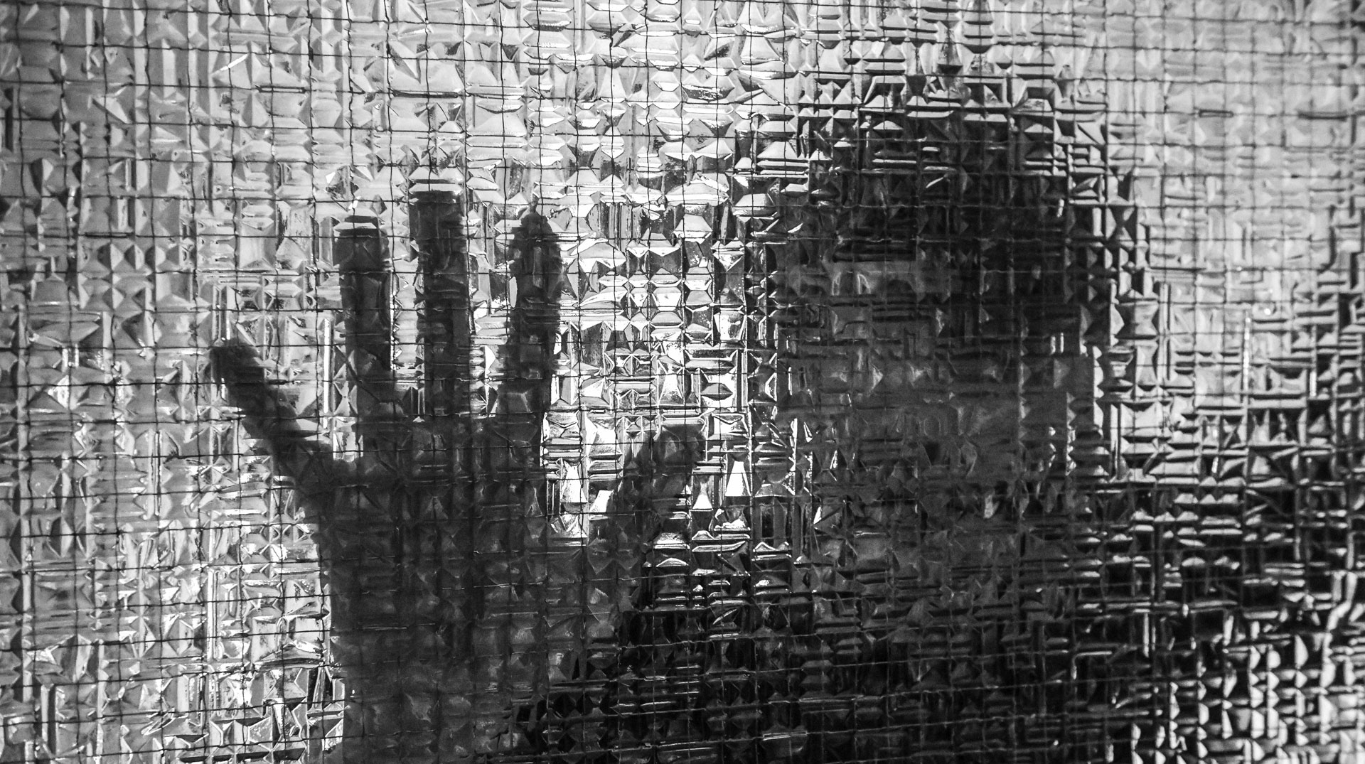 Die unscharfe Silhouette eines Mannes und die Umrisse seiner Hand an einer Glasscheibe am 26. Oktober 2020 in Bonn.