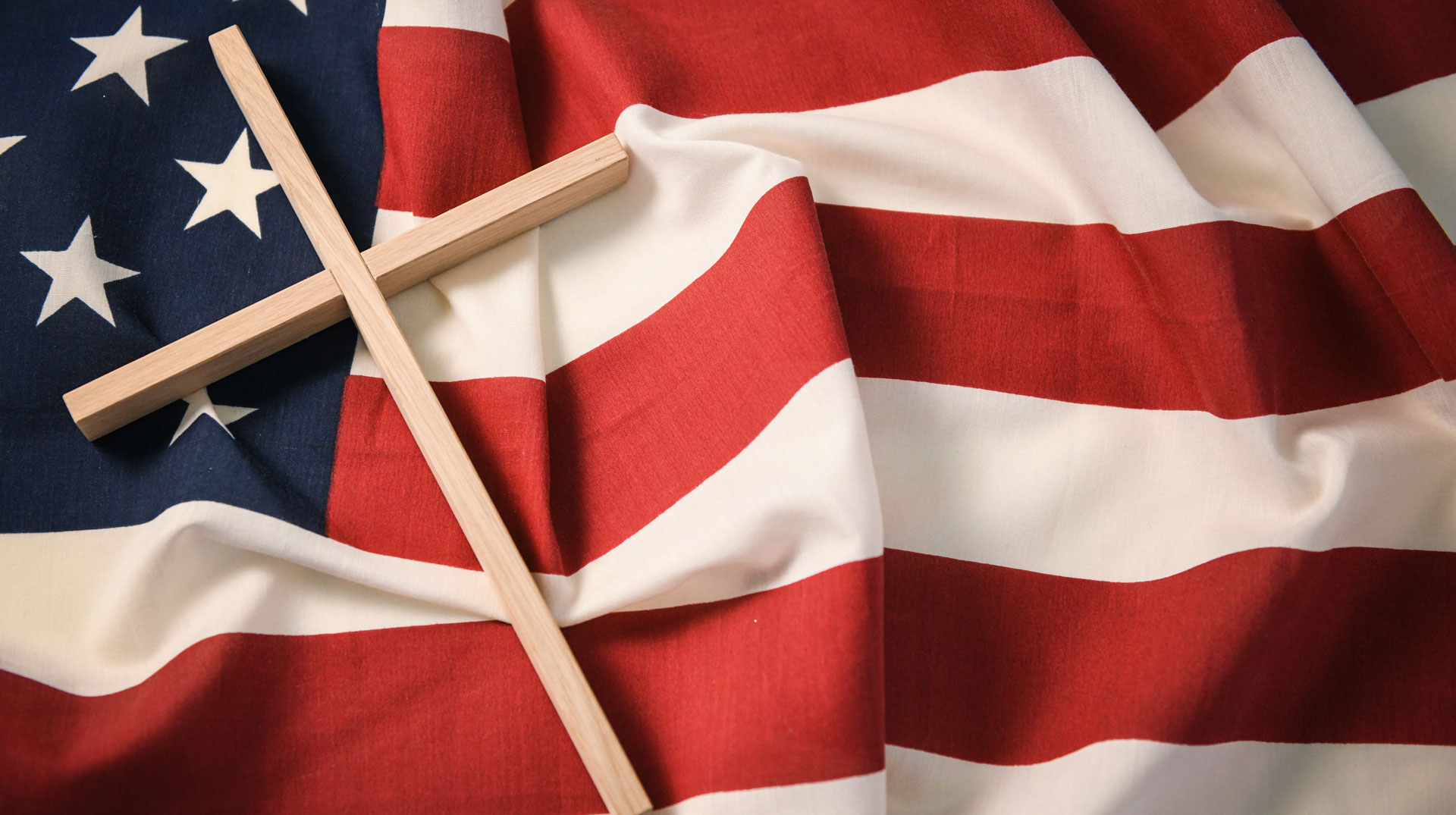 Kreuz liegt auf US-Flagge. Symbolbild Christentum in den Vereinigten Staaten von Amerika (USA)