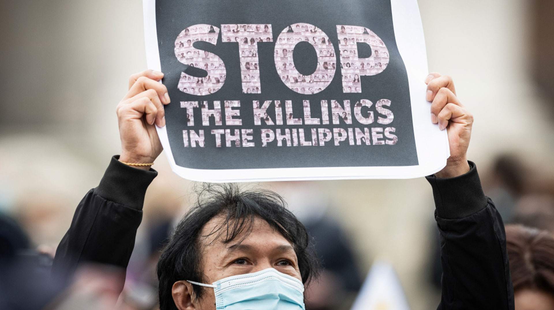 Ein Mann mit Mundschutz hält ein Plakat in die Höhe mit der Aufschrift "Stop the killings in the Philippines" (dt. Stoppt das Töten auf den Philippinen) während des Angelus-Gebets mit Papst Franziskus am 14. März 2021 im Vatikan.