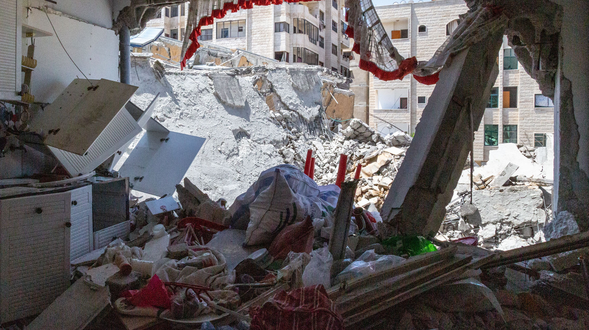 Ein Loch klafft in der Küchenwand der christlichen Familie Al-Sayegh am 4. Juni 2021 im Hafenviertel von Gaza nach einem israelischen Luftangriff. Dahinter ist die Ruine des zerstörten Hanadi-Hochhauses zu sehen.
