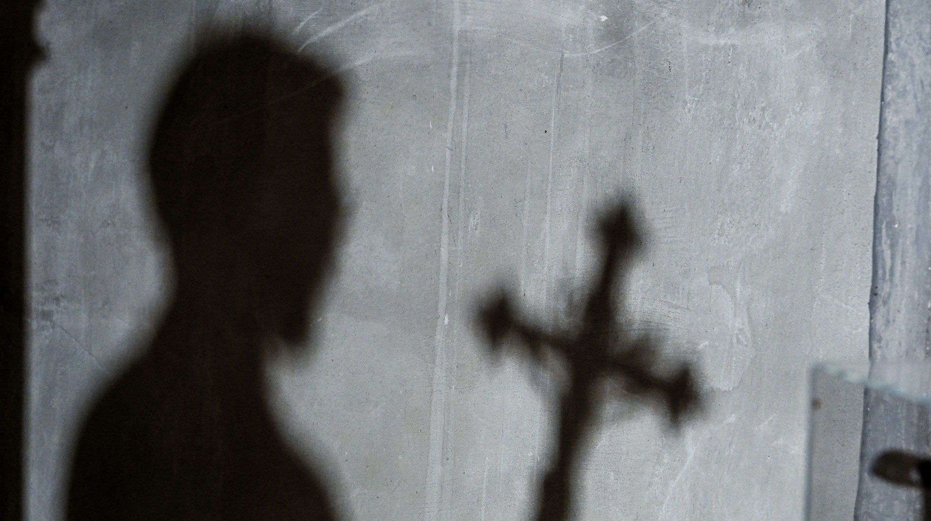 Schatten von Mensch und Kreuz auf einer Wand