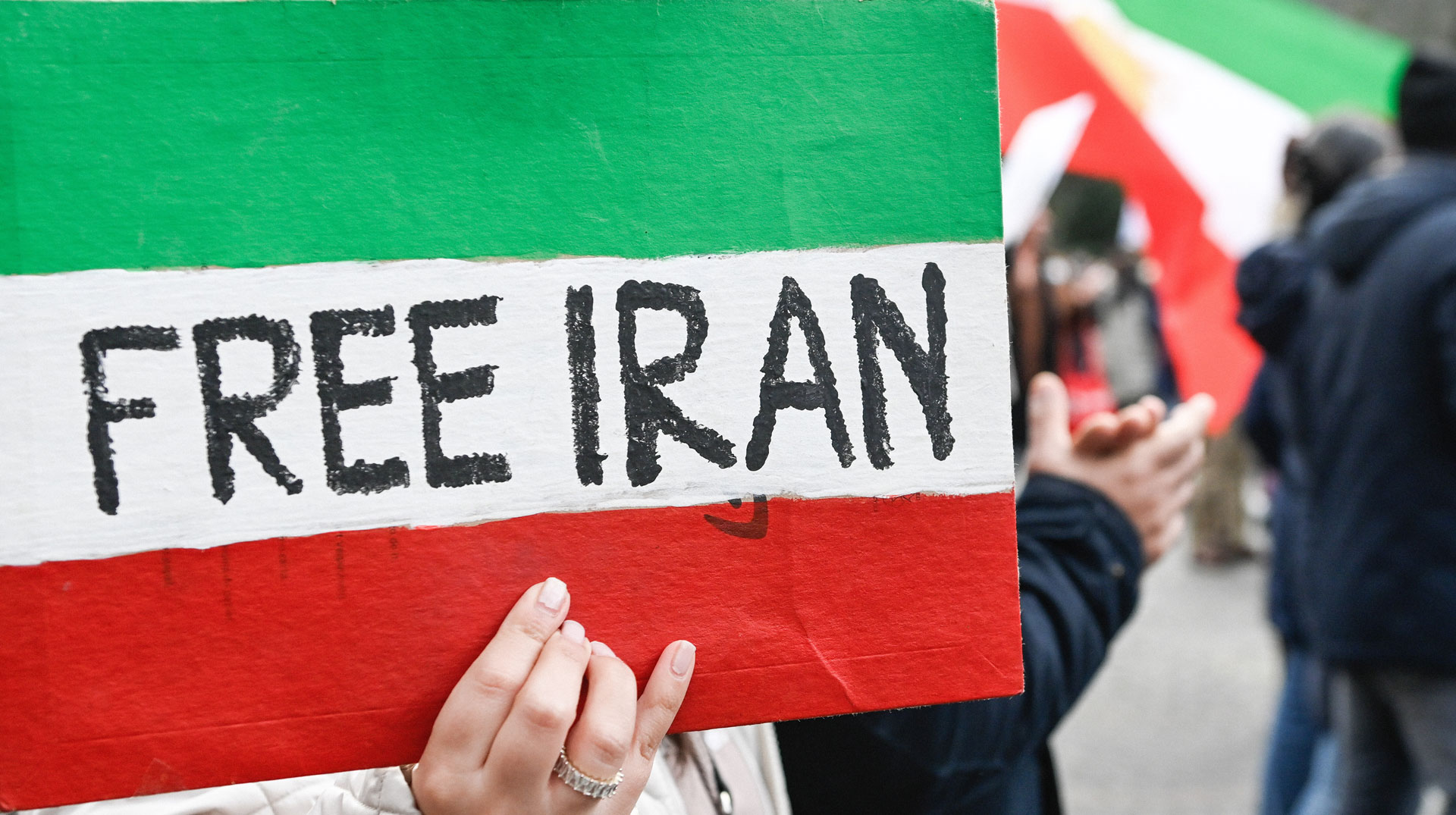  Eine Frau hält ein Schild in den Farben der iranischen Nationalflagge mit der Aufschrift "Free Iran" (dt. Befreit den Iran).