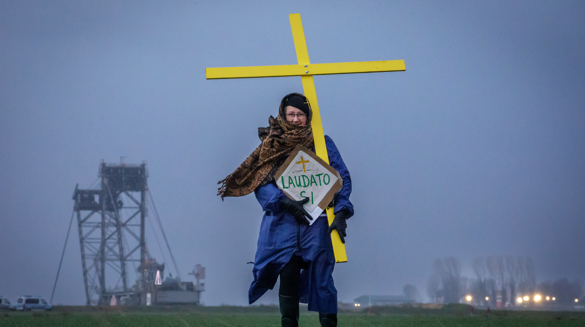 Eine Demonstrantin trägt ein Kreuz und ein Schild mit der Aufschrift "Laudato Si" am 13. Januar 2023 an der Abbruchkante im Gebiet des Tagebaus Garzweiler im Erkelenzer Weiler Lützerath.