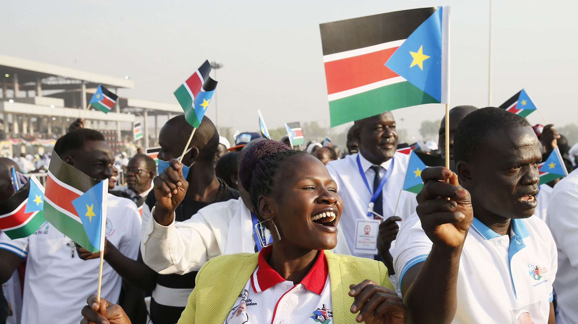 Menschen feiern und schwenken kleine Nationalflaggen vom Südsudan vor der Messe mit Papst Franziskus am 5. Februar 2023 am "John-Garang-Mausoleum" in Juba (Südsudan).