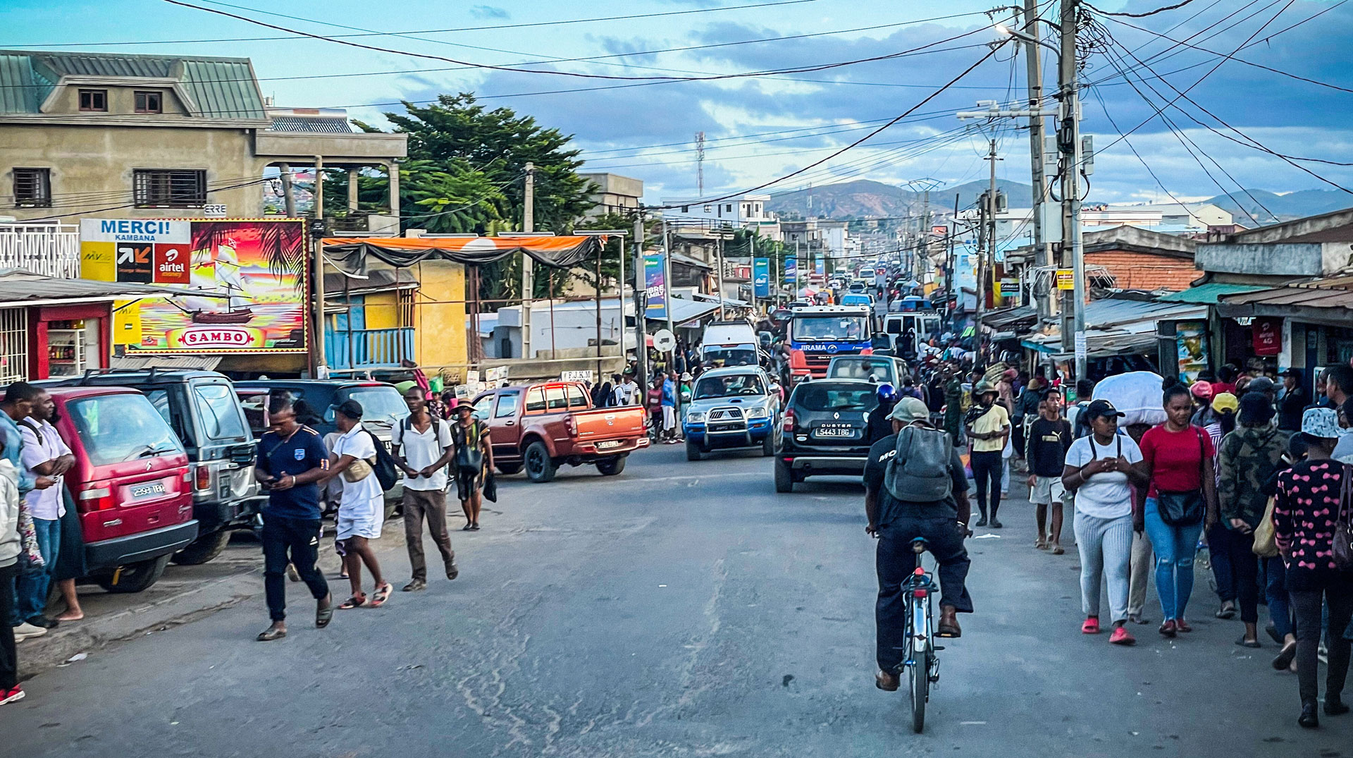 Autos fahren durch überfüllte Straßen und Menschen gehen an Bretterbuden vorbei in Antananarivo (Madagaskar) am 14. Februar 2023.