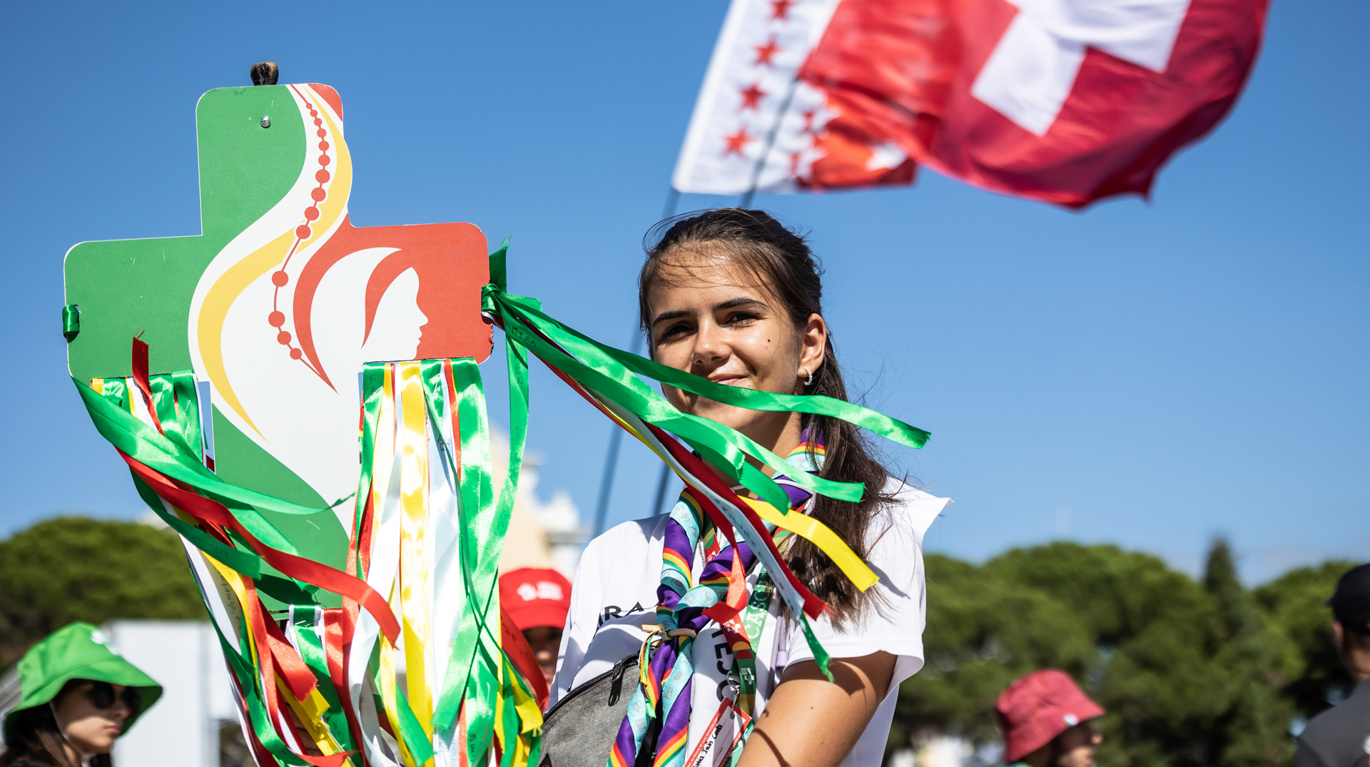 Eine junge Frau trägt ein Kreuz in den WJT-Farben mit Bändern vor der Eröffnungsmesse des WJT in Lissabon (Portugal) am 1. August 2023.