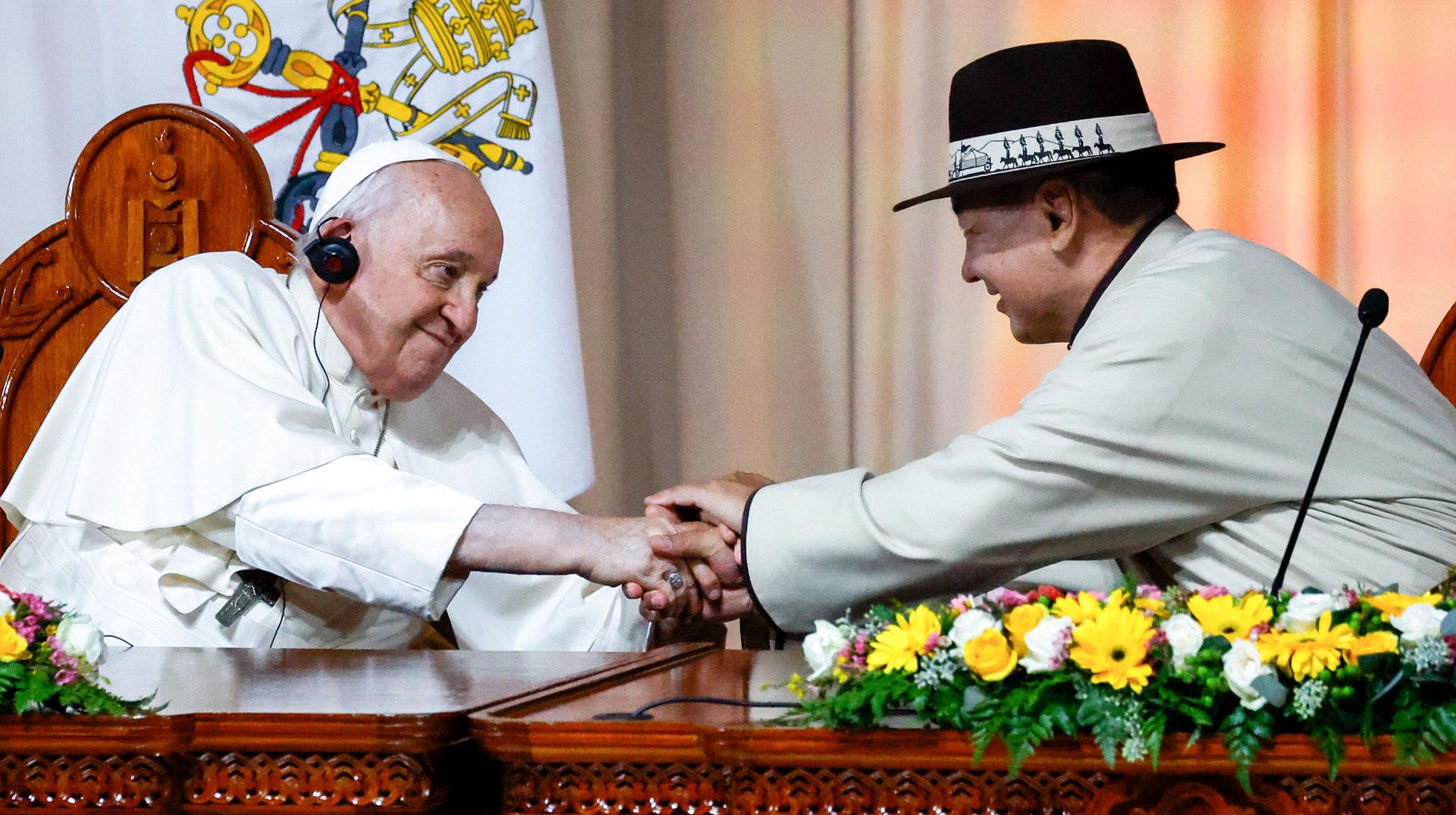 Papst Franziskus und Ukhnaagiin Khürelsükh, Präsident der Mongolei, geben sich die Hände bei einem Treffen mit Vertretern von Regierung, Zivilgesellschaft und Diplomatischem Korps im Staatspalast in Ulan Bator (Mongolei).
