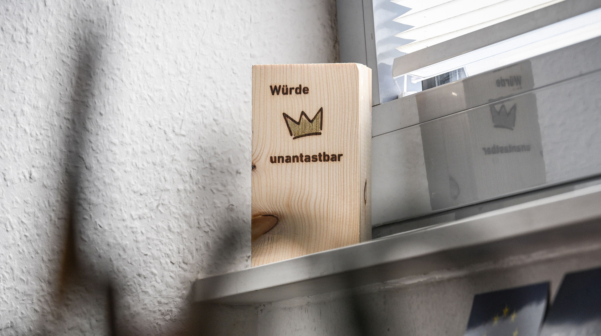 Ein Holzklotz mit der Aufschrift "Würde. Unantastbar." am 12. August 2024 im Büro der Beratungsstelle für Kirchenasyl in einer Kirchengemeinde in Bonn.