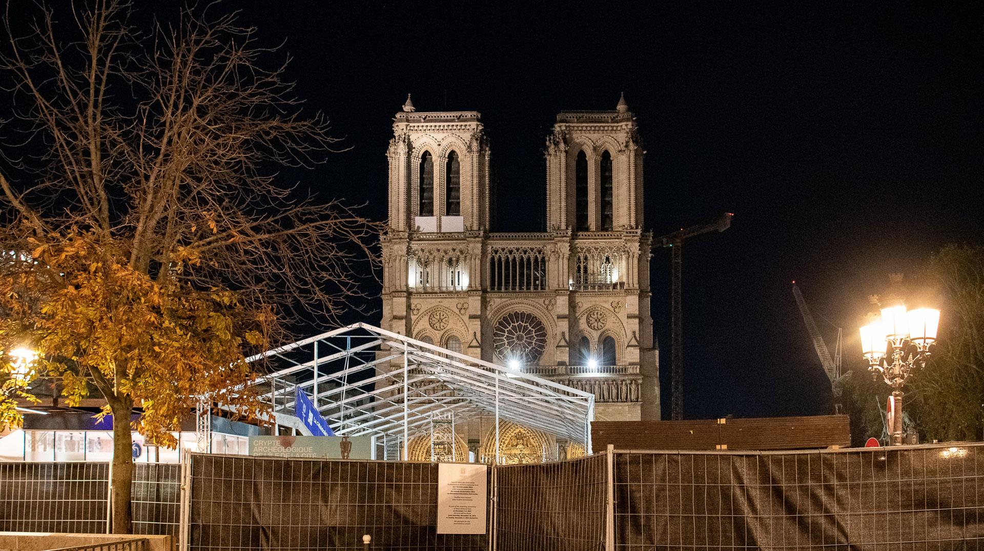 Bauzäune vor der beleuchteten Kathedrale Notre-Dame nachts am 22. November 2024 in Paris (Frankreich).