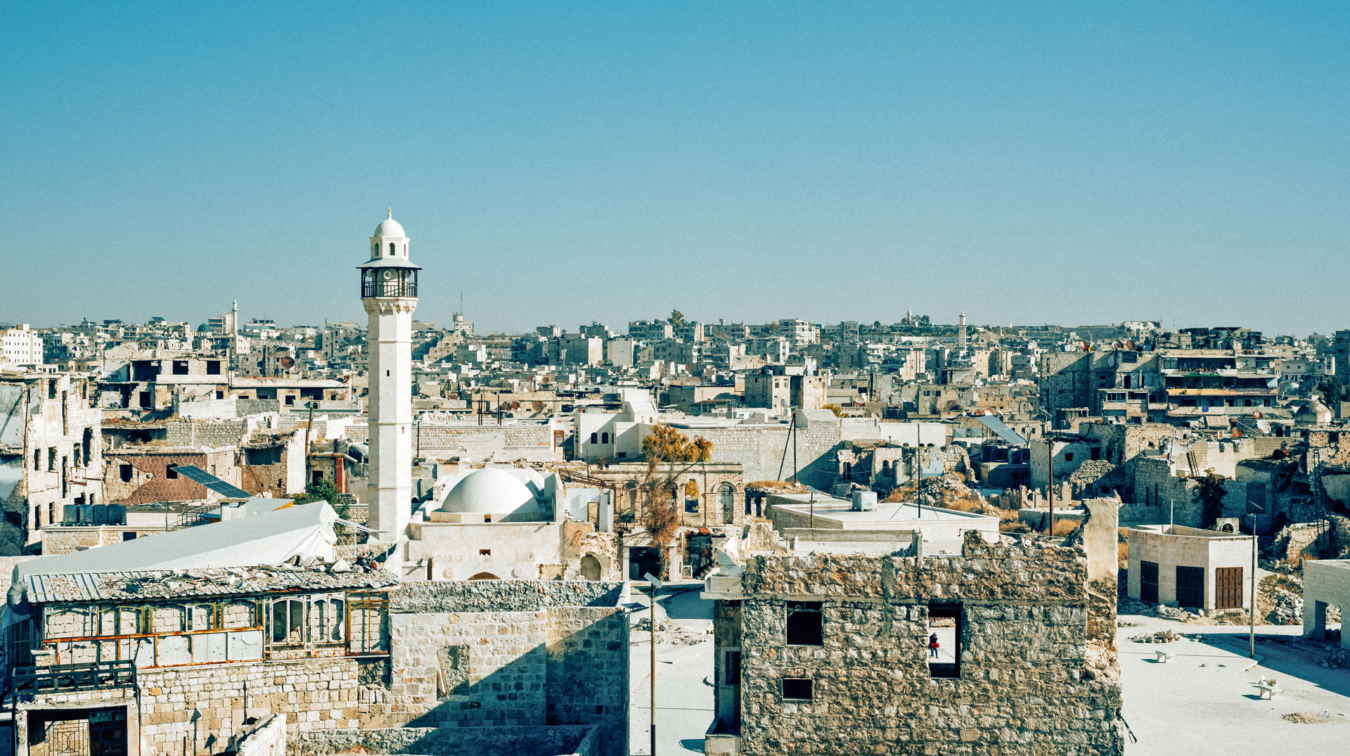 Das Minarett einer Moschee ragt über zerstörte Häuser am 15. Dezember 2024 in Aleppo (Syrien).