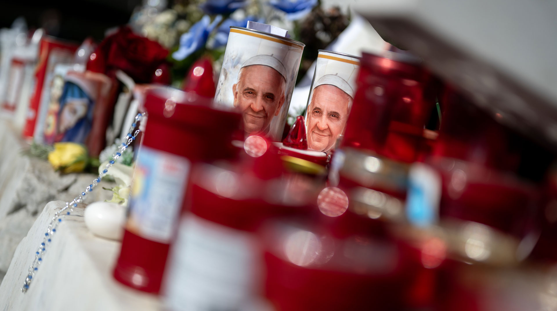 Blumen und Votivkerzen, einige mit dem Abbild von Papst Franziskus, liegen vor dem Gemelli-Krankenhaus in Rom (Italien) am 22. Februar 2025.
