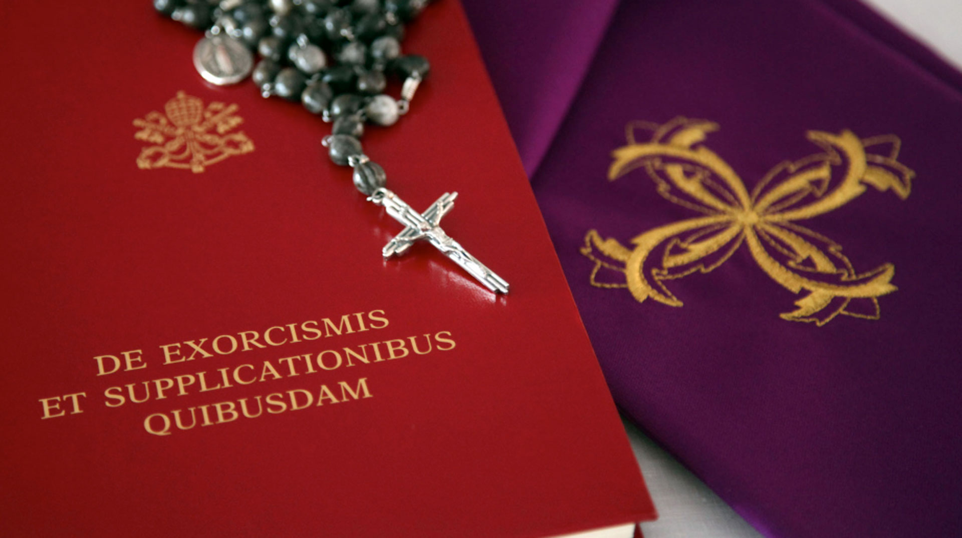 Exorzismus-Handbuch liegt neben einer violetten Stola und einem Rosenkranz