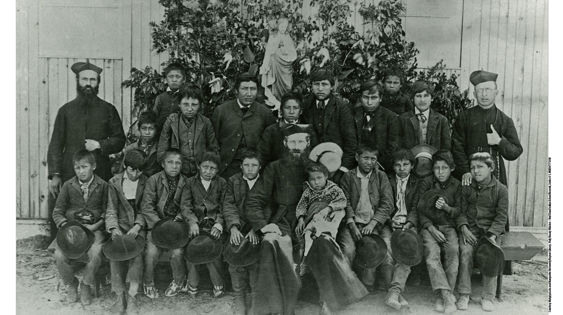 Indigene Schulkinder mit Jesuiten vor einer Statue des Heiligsten Herzens Jesu in South Dakota (Boarding School)