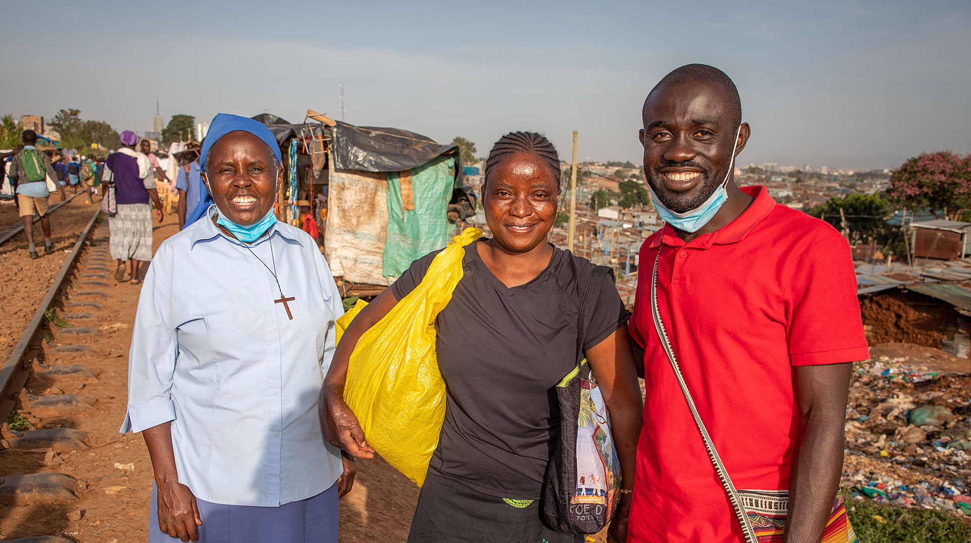Drei Personen stehen auf Schinen in Kibera (Nairobi)