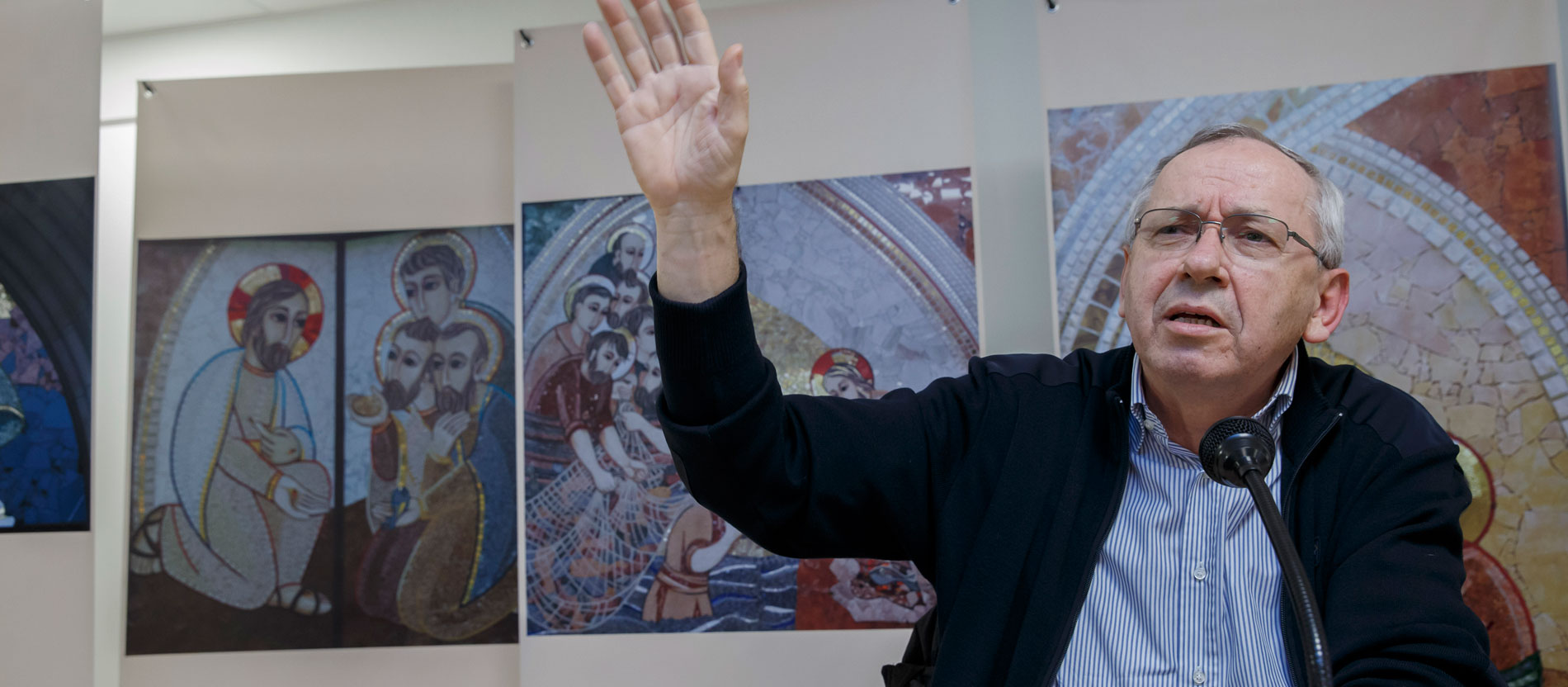 Father Marko Rupnik in front of pictures of his mosaics