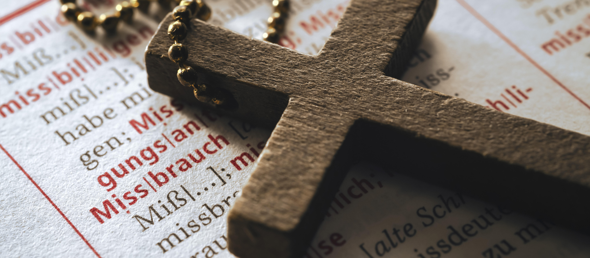 A cross lies on a dictionary with the keyword "abuse"