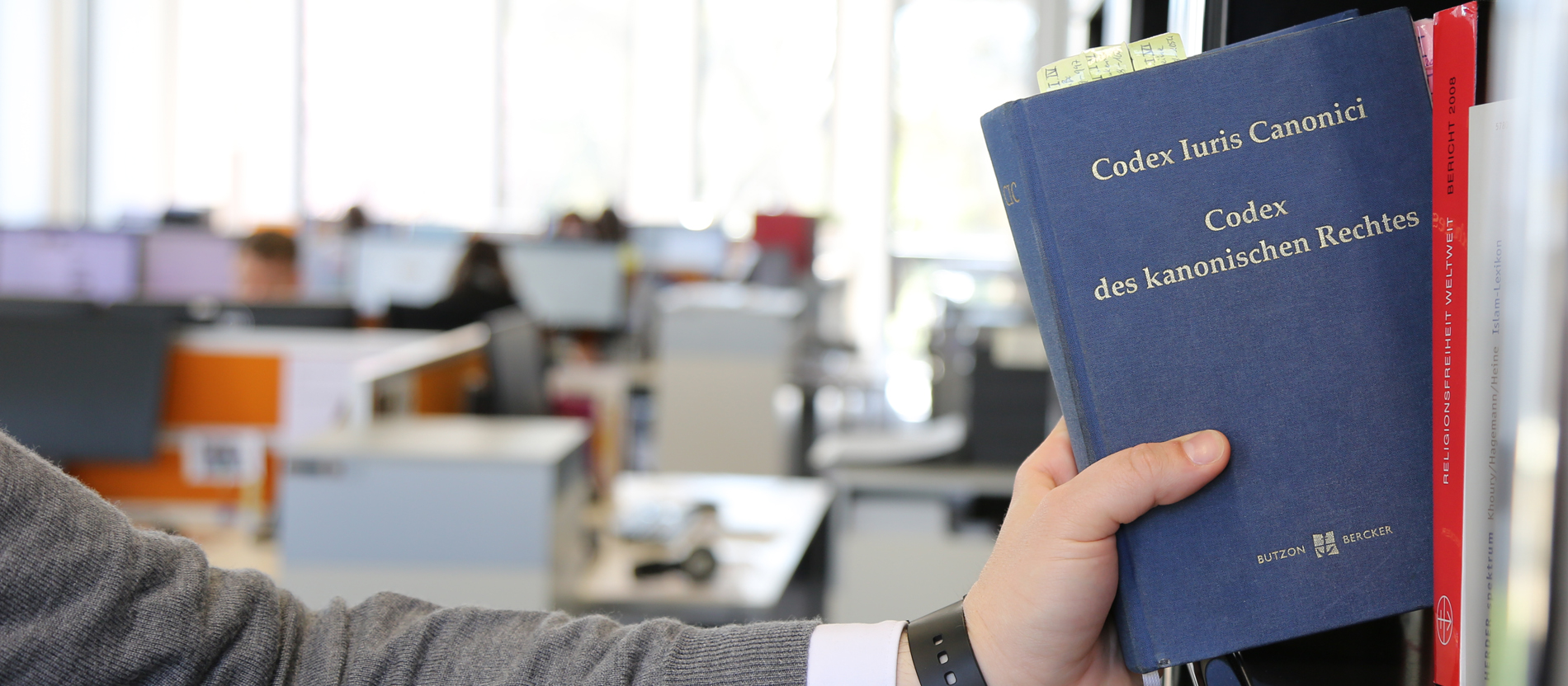 A man takes the Code of Canon Law from a shelf.