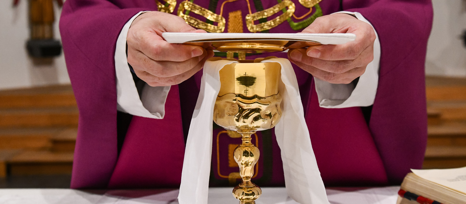 A priest places the palla on the chalice during a divine service.