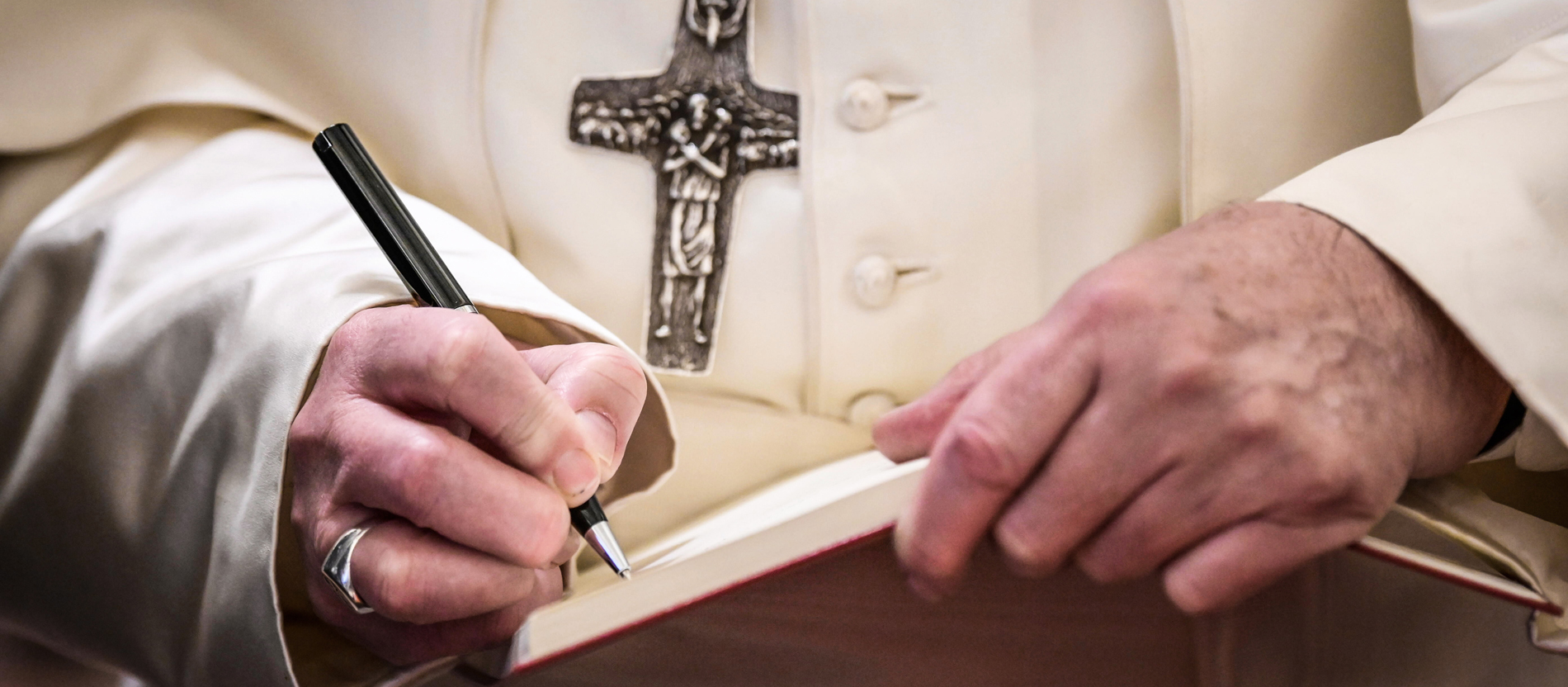 Pope Francis writes with a biro in a notebook