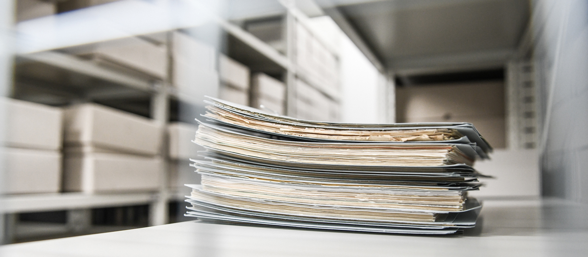 Akten liegen gestapelt im Regal eines Bistumsarchivs