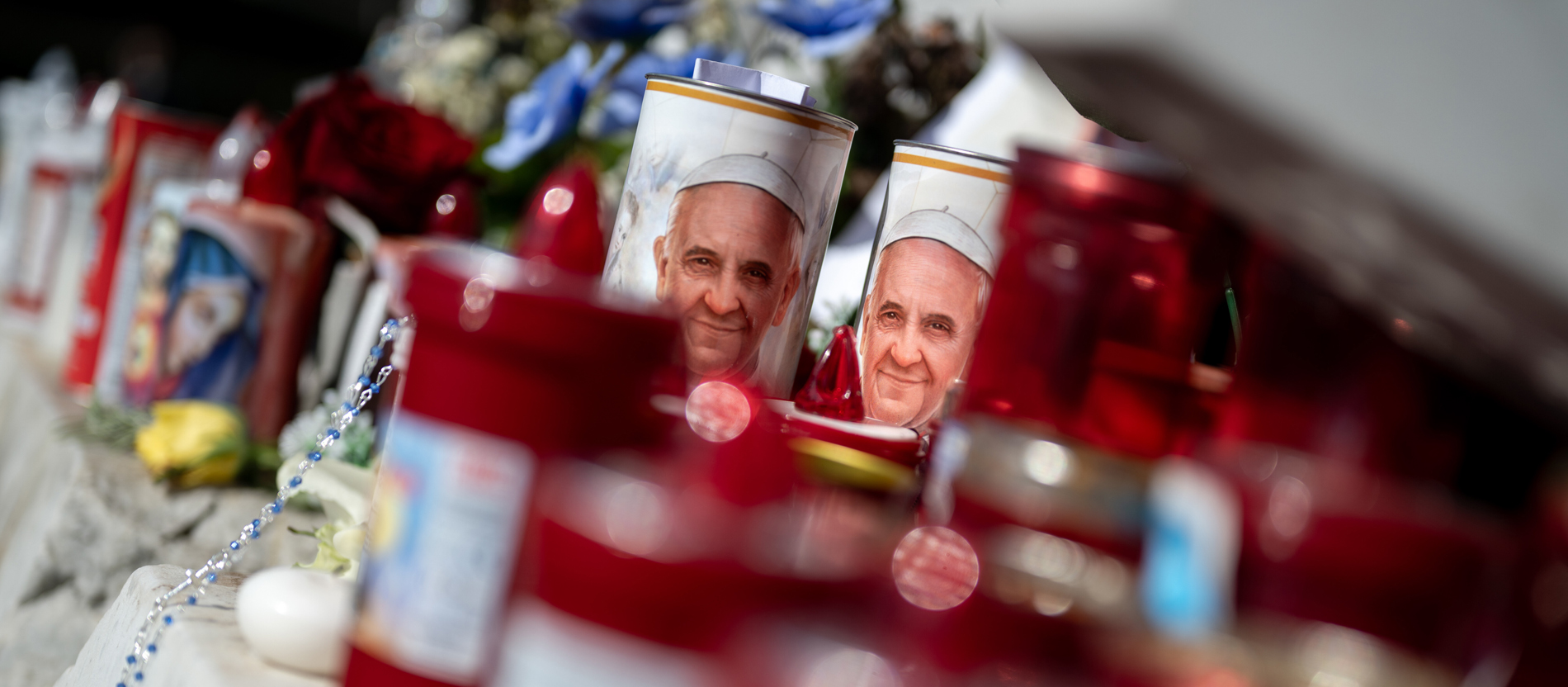 Blumen und Votivkerzen, einige mit dem Abbild von Papst Franziskus, liegen vor dem Gemelli-Krankenhaus in Rom
