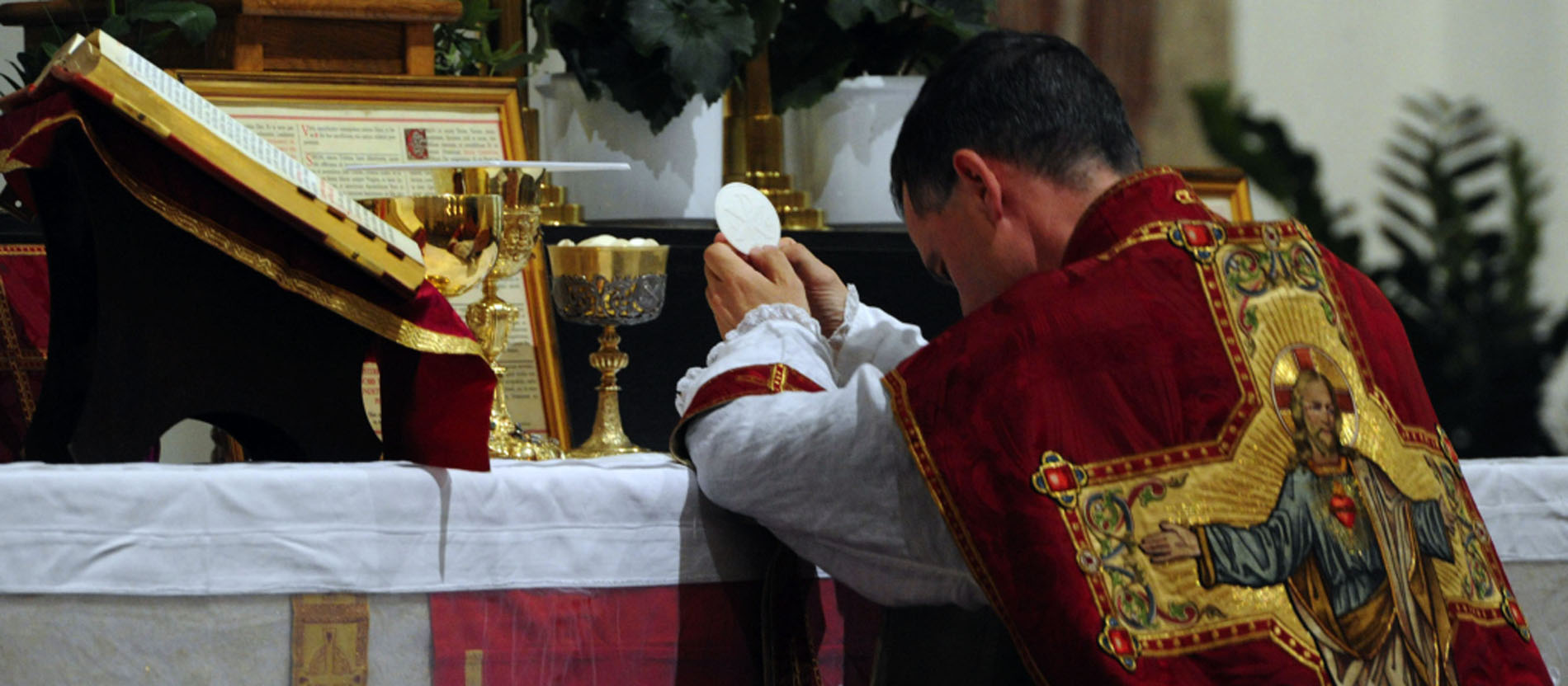 A priest makes a genuflection before the consecrated host