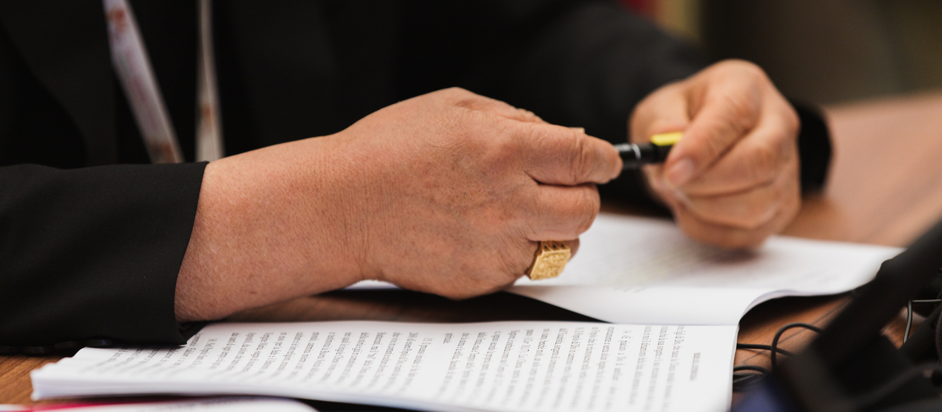 A bishop closes a pen, under his hands lies the final document of the World Synod
