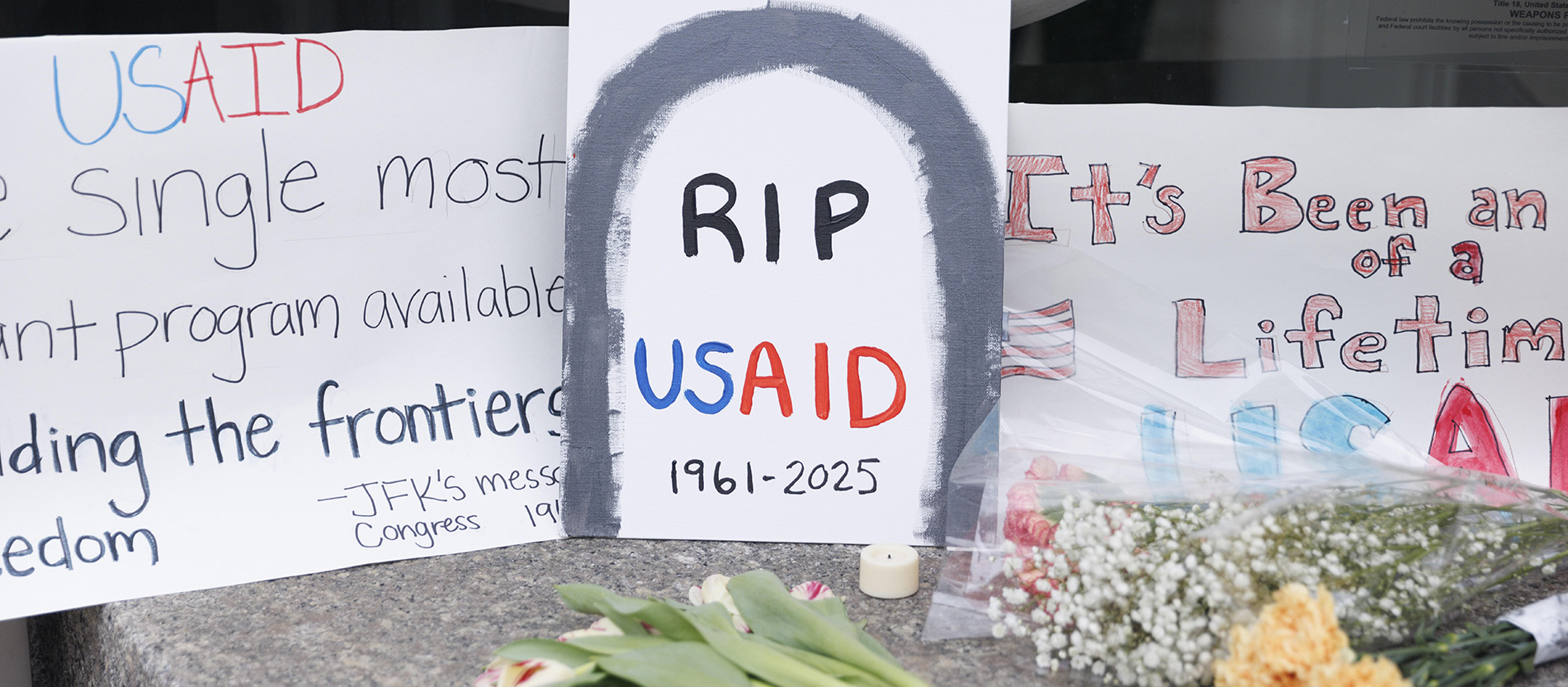 Plakate und Blumen mit der Aufschrift RIP USAID