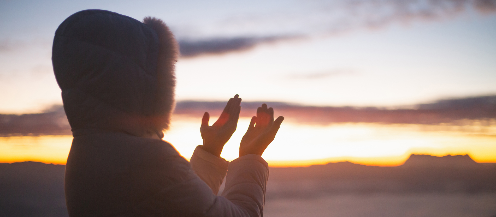 Eine Frau betet bei Sonnenaufgang